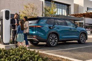 2027 Toyota Highlander EV inspired electric SUV charging at a modern US suburban charging station